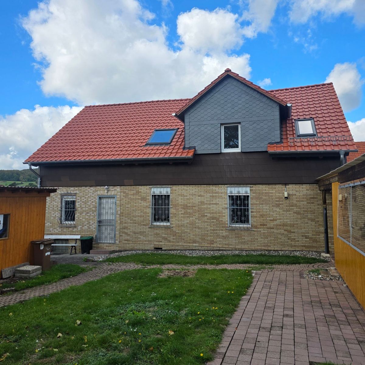 Neu eingedecktes Dach mit roten Dachziegeln und Schiefergaube