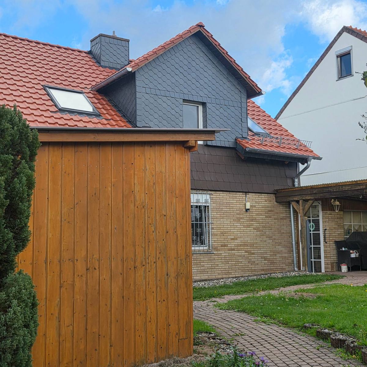 Seitenansicht nach der Dachsanierung mit neuer Ziegeleindeckung und Schiefergaube