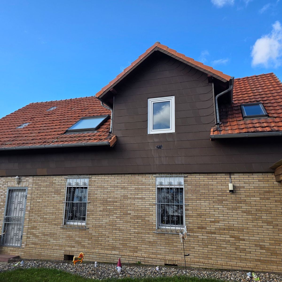 Haus mit alter Dacheindeckung und brauner Verkleidung vor der Sanierung
