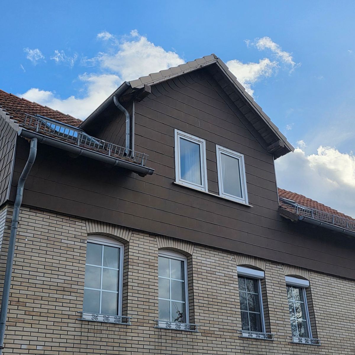 Alte Gaube mit brauner Verkleidung und Dachrinne vor der Sanierung